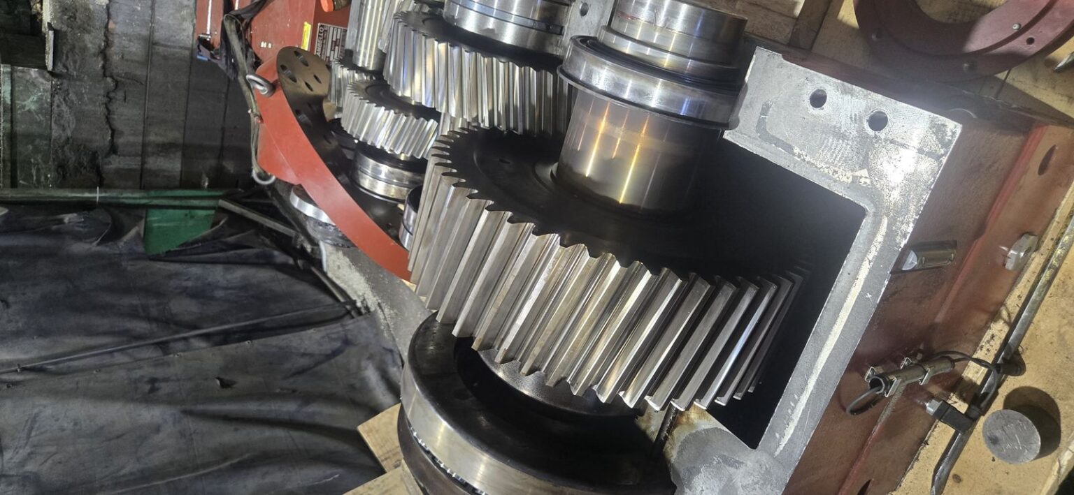 Gear train reassembled and re-timed inside an industrial extruder gearbox housing