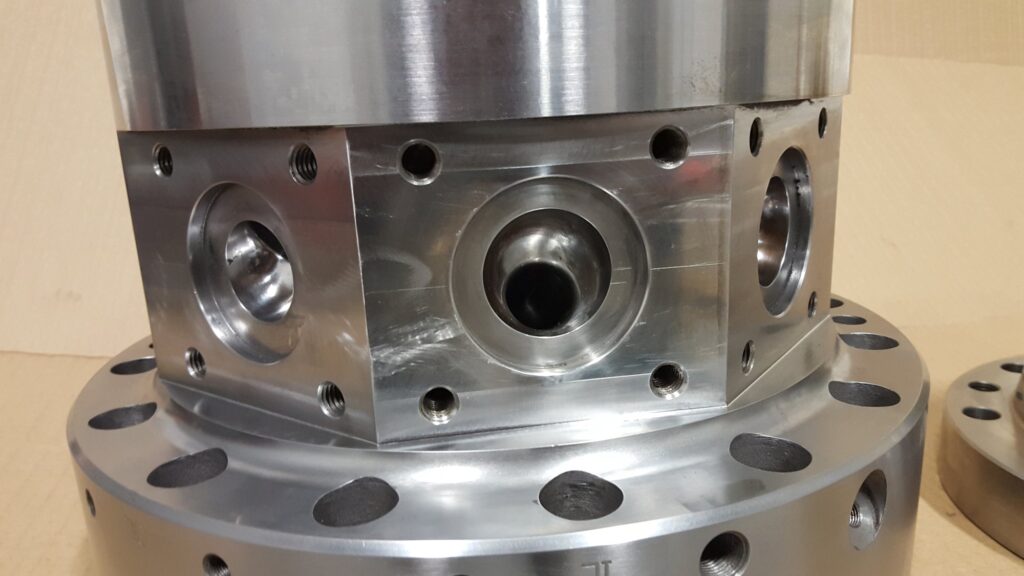 Melt ports bored and tapped into the milled flats of a blown film die body on its base flange