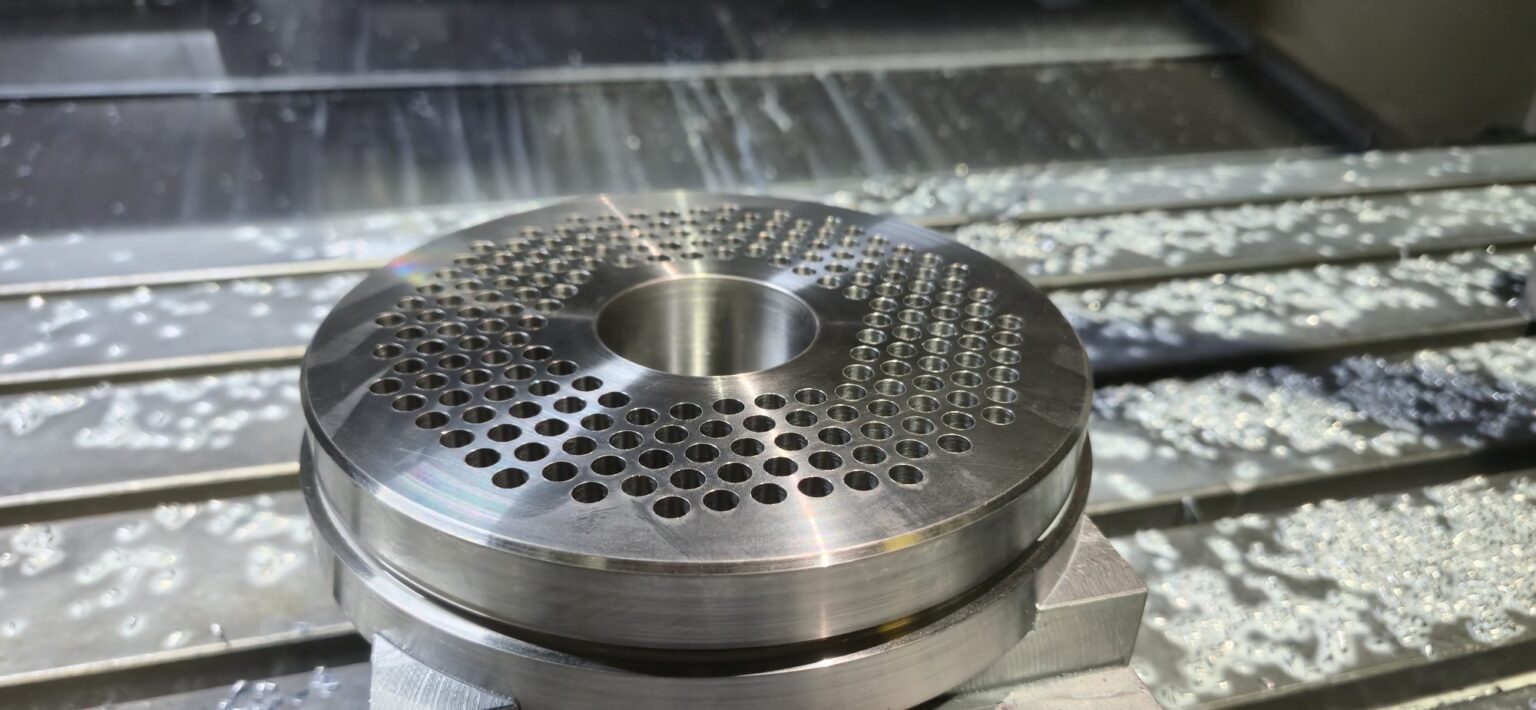 Close view of breaker plate holes drilled on the CNC mill, chips on the table