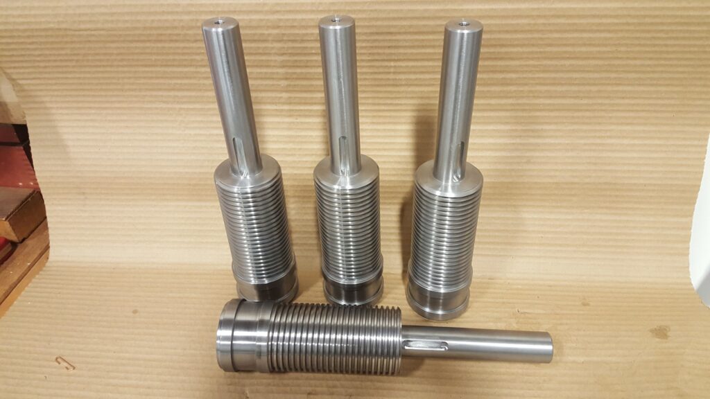 Four CNC-turned shafts from one run, coarse threads and milled keyways, finished on the bench