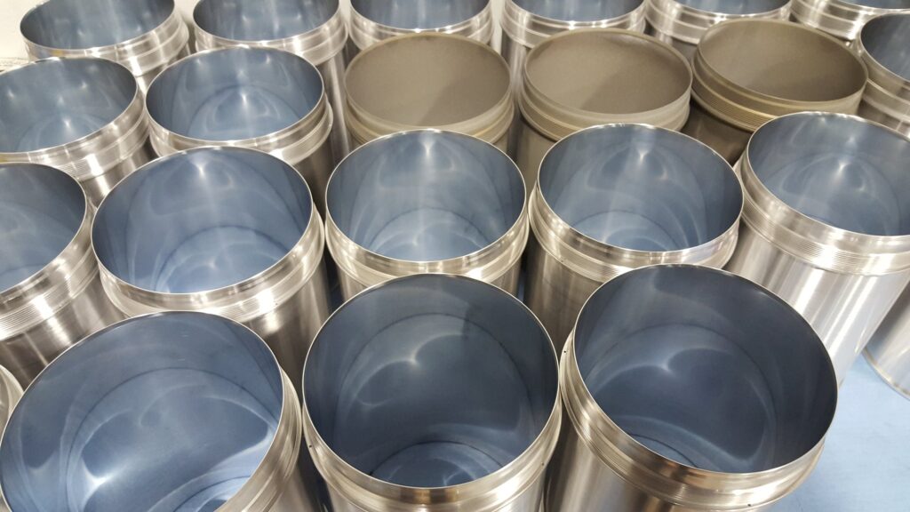 Production run of machined stainless cylinders lined up, every bore finished to the same size
