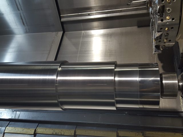 Multi-diameter machined shaft resting on the lathe bed