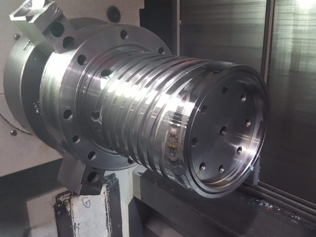 Spiral mandrel being machined showing helical flow channels and bolt flange