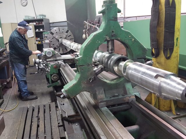 Machinist setting up a long shaft on the large lathe at Zala Machine Co.