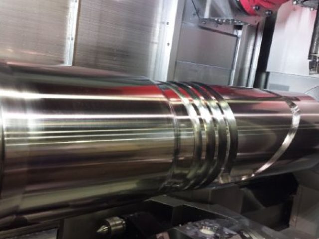 Polished steel shaft mounted in a lathe during precision turning