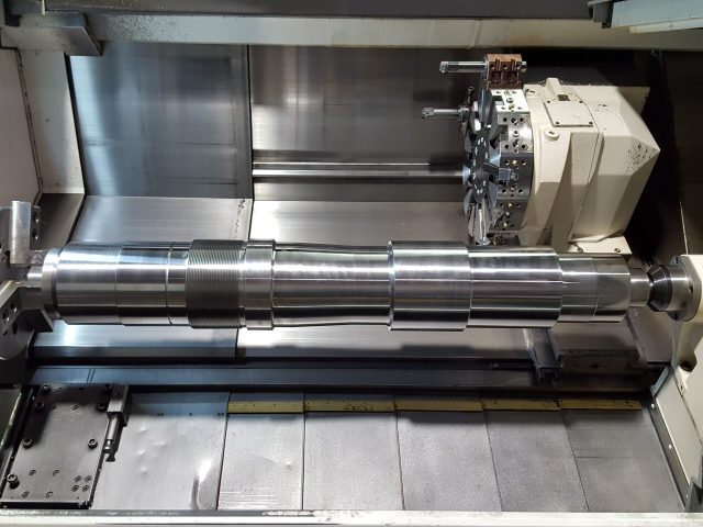 Machined industrial shaft on the lathe bed