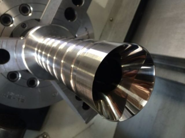 Tapered fluted stainless steel component being turned in a CNC lathe chuck at Zala Machine Co.