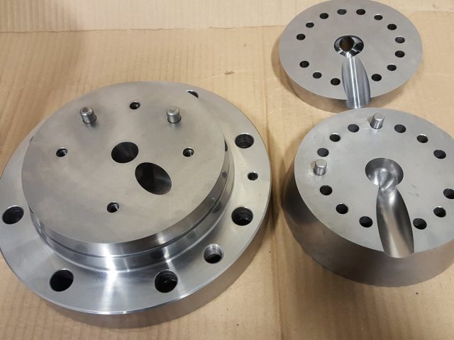 Set of blown film die distribution plates, each with its teardrop melt port and dowelled bolt pattern