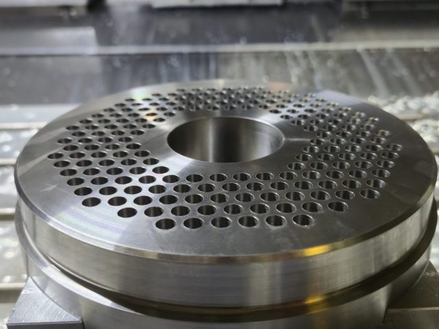 Breaker plate on the mill table after drilling, hole pattern and center bore