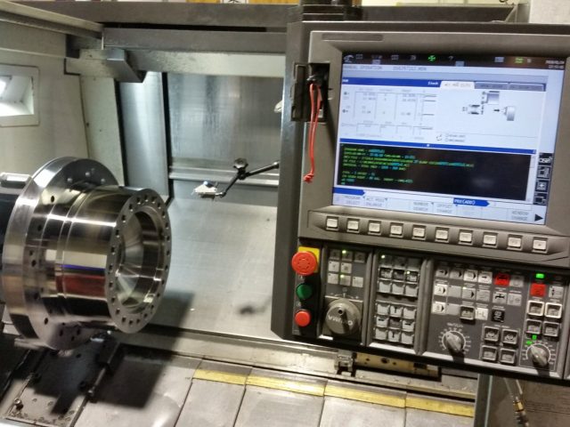 Large flanged hub running in the CNC lathe, program up on the control alongside