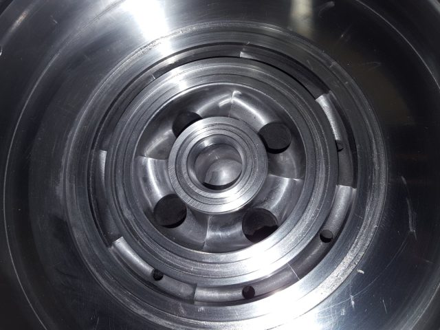 Inside a die flow distributor, radial vanes and ports machined around the concentric centre boss