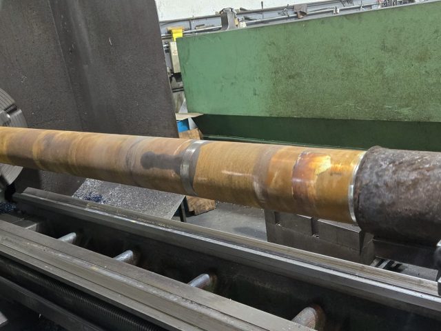 Rusted extruder barrel set up on the large engine lathe for repair