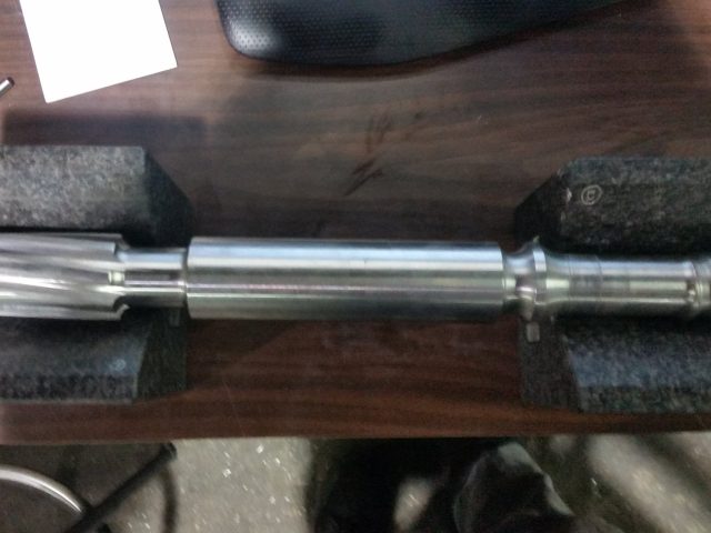 Finished screw shaft set on granite blocks, fluted drive end at one side and the flighted section at the other