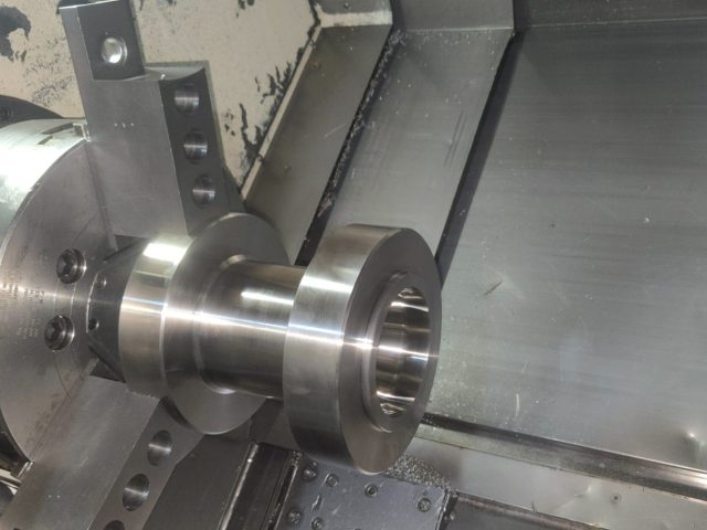 Stepped spool with machined flange set up on the lathe