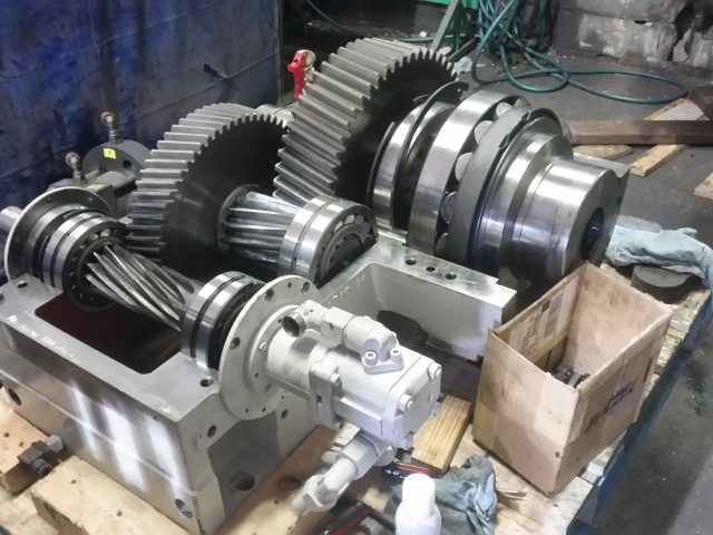 Gear and shaft assembly resting on its housing base, large helical gears and splined coupling