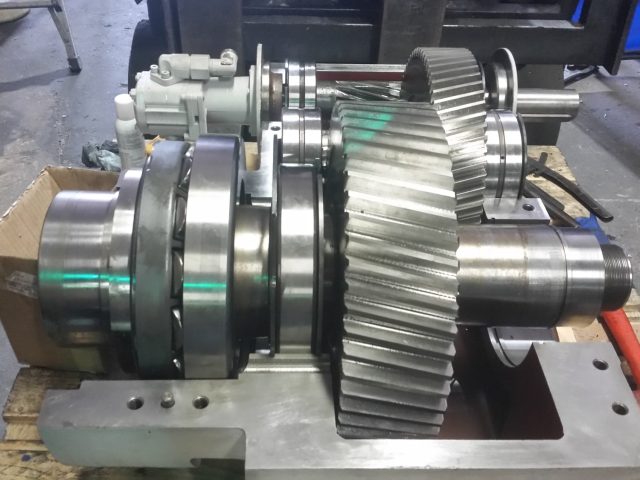 Gearbox gear train assembled on the stand, large helical gear meshed with its pinion shaft and bearing stack