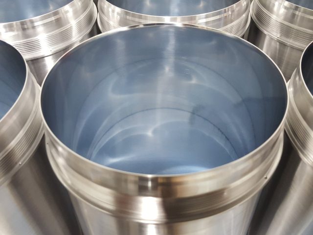 Batch of stainless steel cylinders with honed bores, the finish reflecting straight down the bore