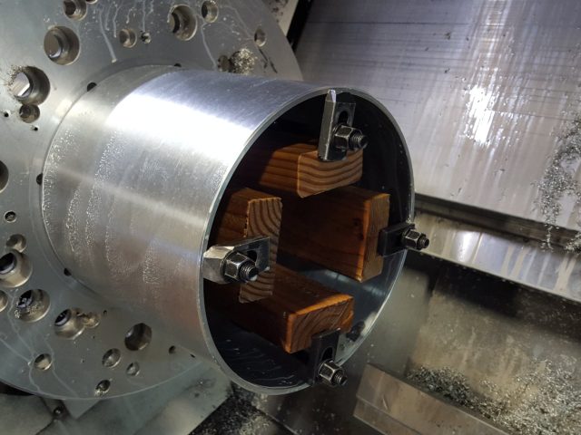 Large cylinder body bored on the lathe, timber packing braced inside to hold it round under the clamps