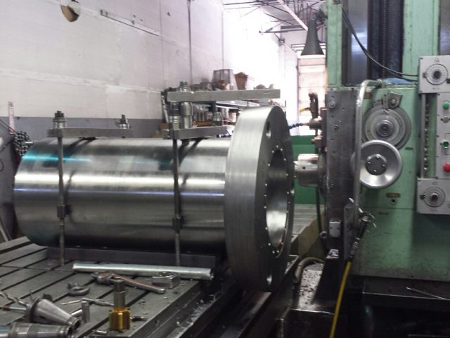 Long cylinder housing clamped on the horizontal boring mill table, flange face toward the spindle
