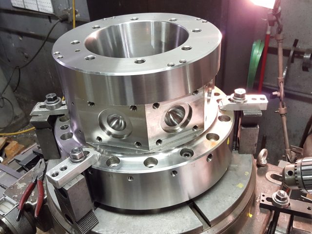 Large stainless housing clamped on the machine table, flange bolt circle and side ports machined