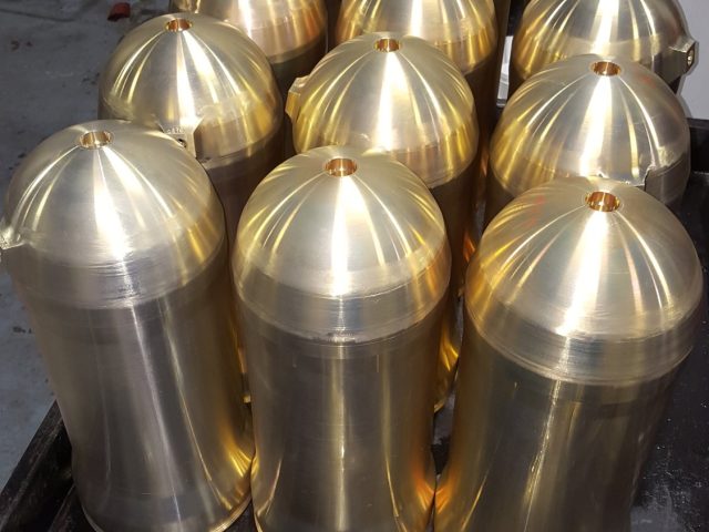 Batch of bronze bullet-nose parts turned and polished, standing together on the bench