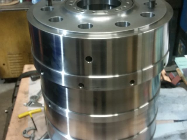Machined cylindrical housing finished on the bench, stacked sections bolted at the top flange