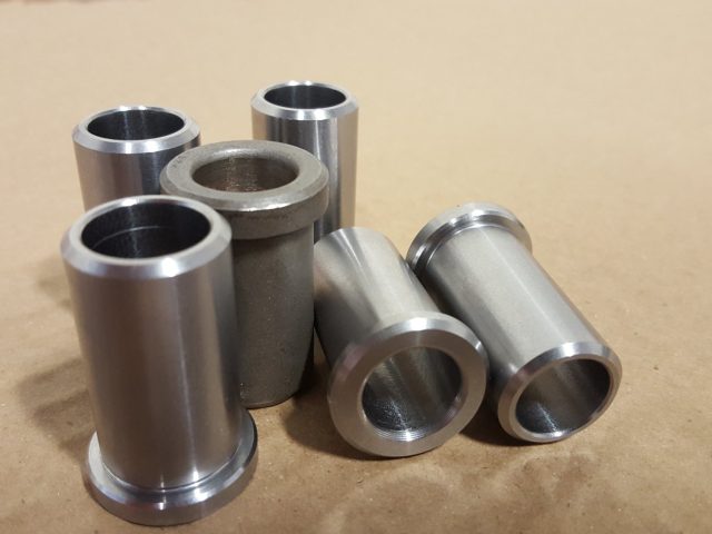 Batch of machined stainless bushings and flanged sleeves grouped on the bench
