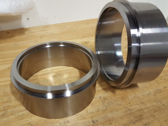 Matched pair of machined steel rings on the bench, bores finished and lips chamfered