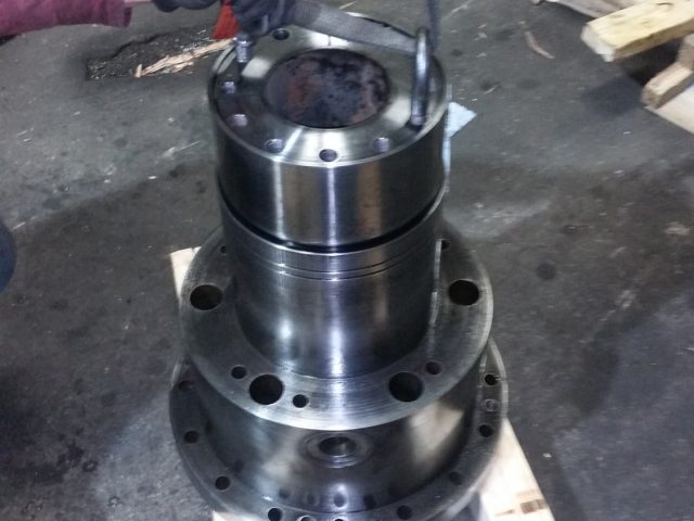 Machined body lifted on slings from its lifting eye, timber blocks set to land it on