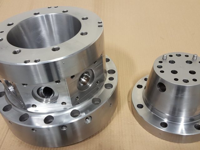 Two finished multi-layer blown film die components side by side, side ports and drilled port face