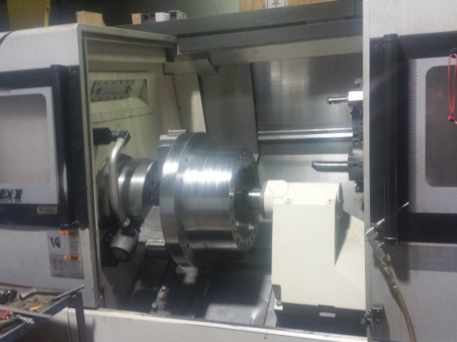 Okuma LB4000EX II turning a flanged part, doors open on the shop floor