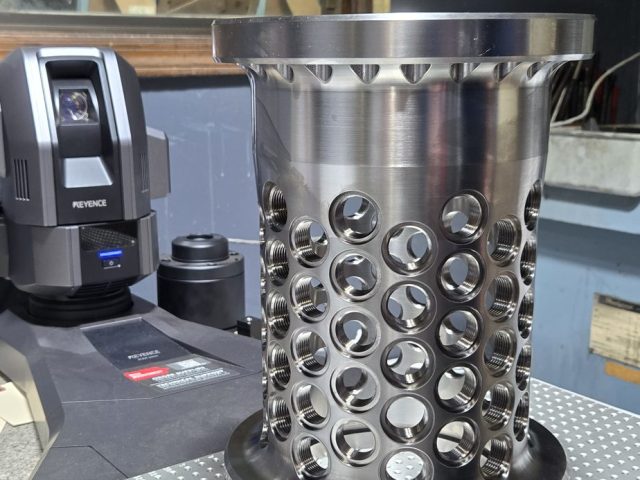 Finished titanium prototype cylinder with radial holes on the inspection table