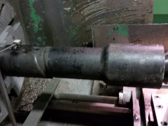 Long steel shaft set up between centres on the manual engine lathe