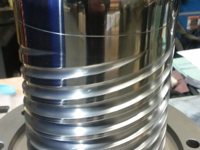 Spiral mandrel standing upright on its bolted mounting flange, flights spiralling up to the polished body